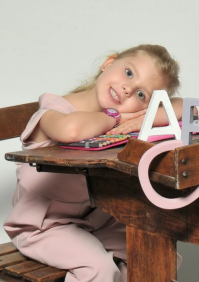 Mädchen zur Einschulung an der alten Schulbank im Studio